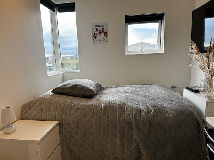 Spavaća soba na srednjem katu s bračnim krevetom, televizorom, ormarom i malim radnim stolom. 