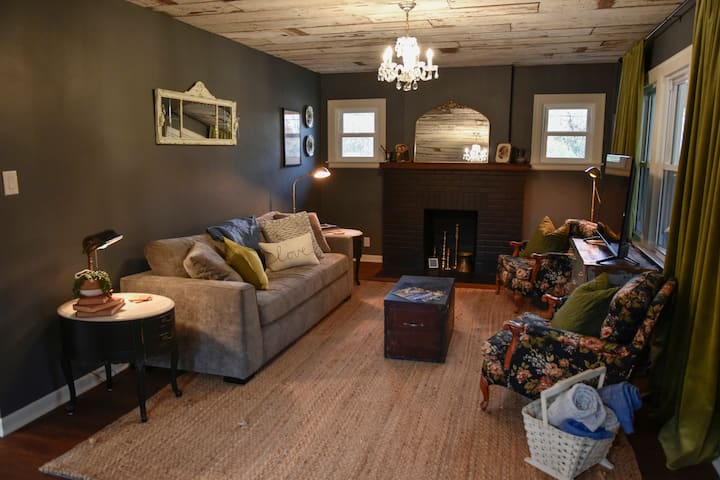 Gather around the brick fireplace and sink into the floral armchairs for slow mornings, movie nights, or quiet conversations. Every detail—from brass accents to antique artwork—adds to the farmhouse’s nostalgic warmth.