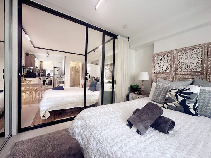 El dormitorio incluye una cómoda cama tamaño queen con sábanas limpias. Una puerta corredera de vidrio con cerradura la separa de la sala de estar para mayor privacidad. Ideal para dos huéspedes, uno en la cama queen y el otro en el sofá cama.