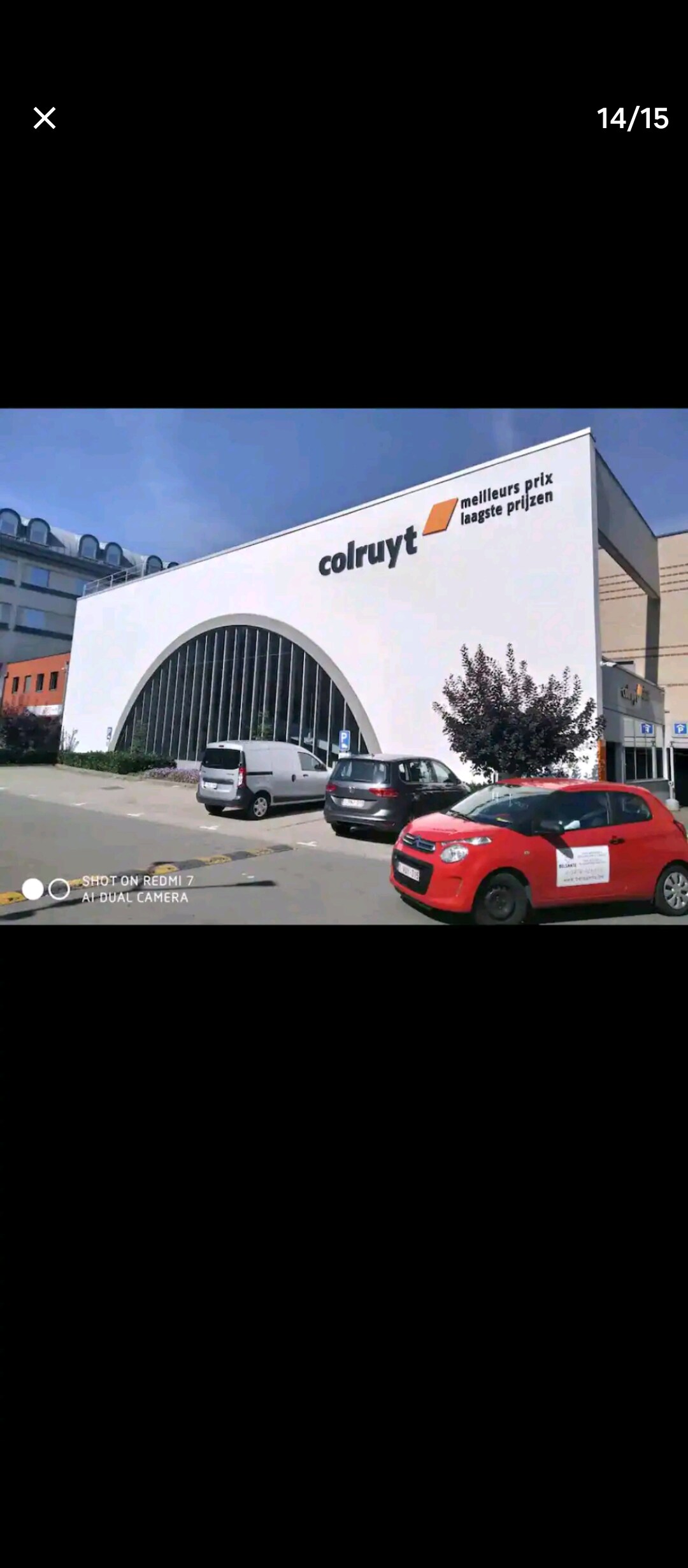 The exterior of a modern grocery store is displayed, featuring a prominent arched design and a bright white facade. The store's name is clearly visible on the side. Vehicles are parked in front, providing a sense of accessibility and convenience in the surrounding area.