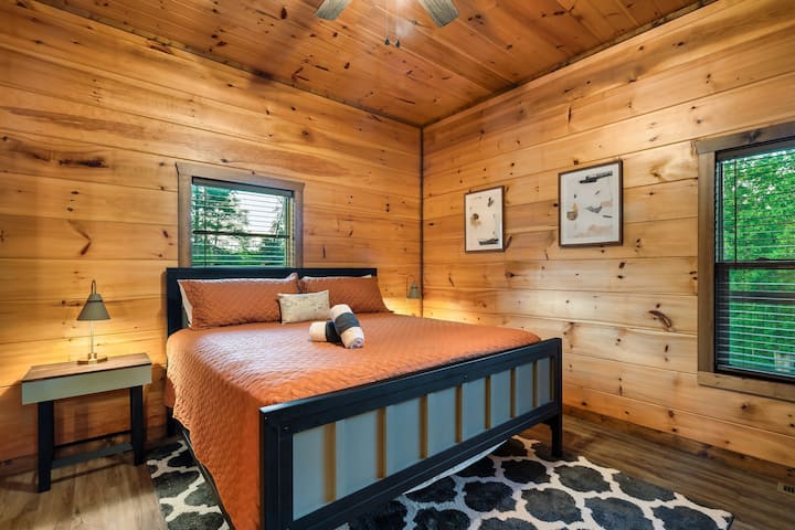 Unwind in a spacious king suite featuring a custom-made bed, warm wood accents, and natural light—perfect for restful nights and serene mornings in the mountains of Pigeon Forge, TN.