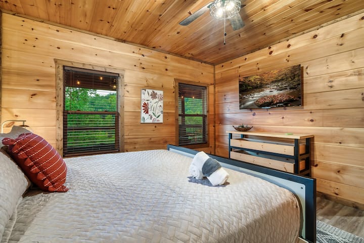 Unwind in a spacious king suite featuring a custom-made bed, warm wood finishes, and lush views through every window. This serene retreat promises restful nights and a true mountain cabin experience.