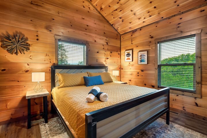 Wake up to breathtaking mountain views in this top-floor king suite, featuring a custom-made bed, vaulted ceilings, and serene natural light for a restful Smoky Mountain retreat.