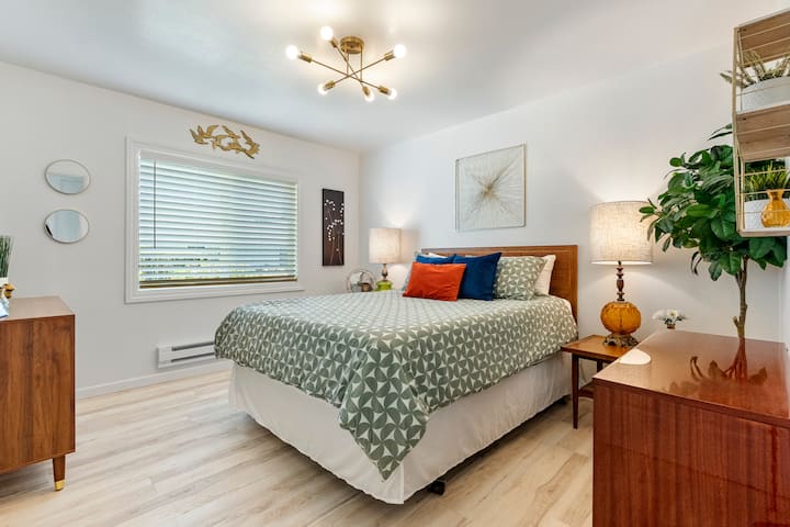 Bedroom 1 offers a stylish and cozy retreat. Relax on the comfortable bed under a unique sputnik chandelier, surrounded by warm wood tones and classic 60's reading lamps