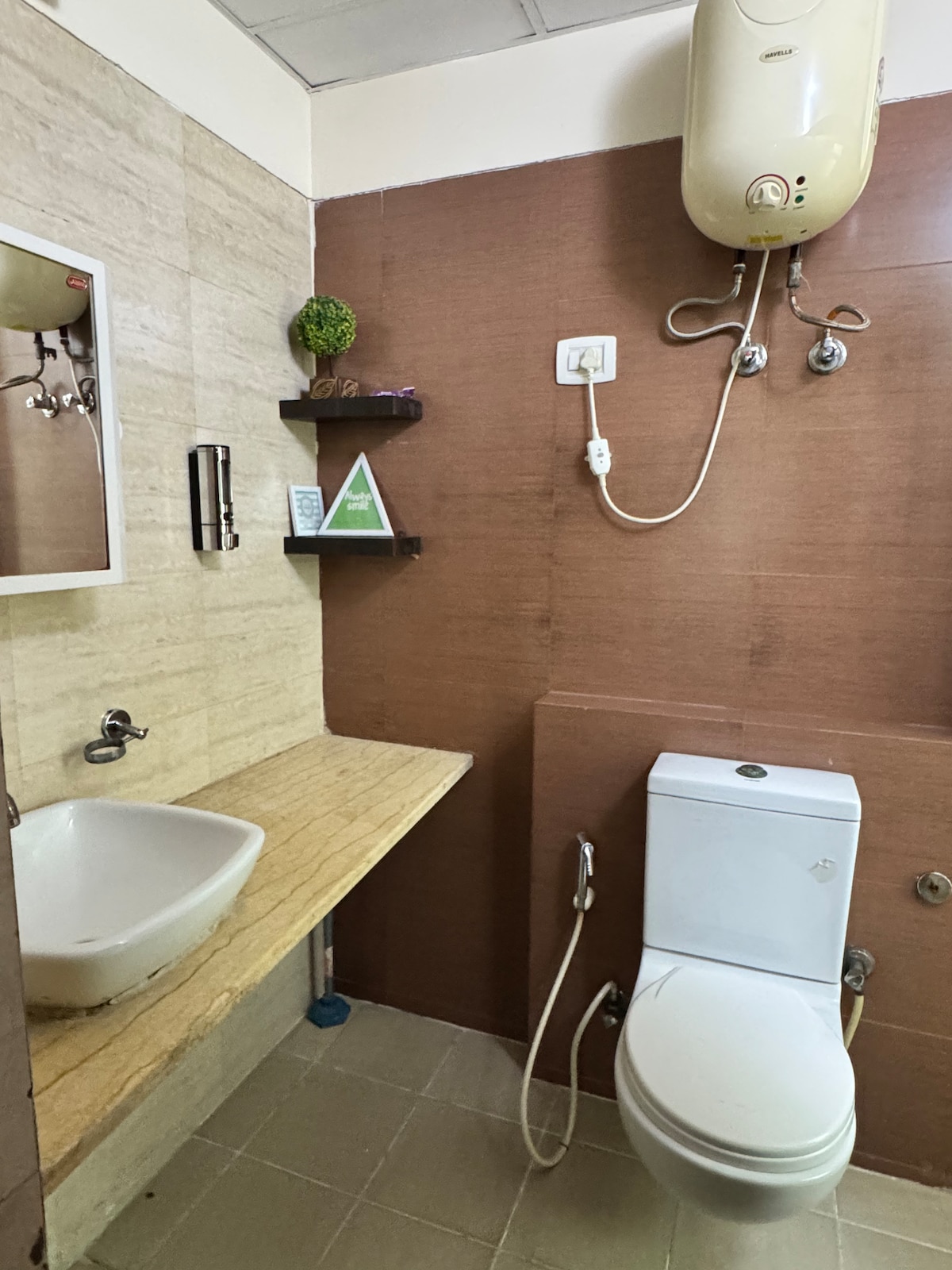 A modern bathroom is featured, showcasing a wall-mounted mirror above a stylish sink with a natural stone countertop. The space is complemented by a toilet fixtures and shower heads, with a small shelf for toiletries. Neutral tones create a clean and simple aesthetic.