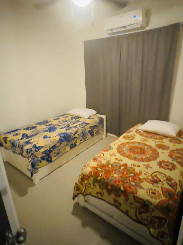 Chambre au centre avec 2 lits jumeaux et un placard entièrement fermé. Table et fer à repasser dans le dressing. 