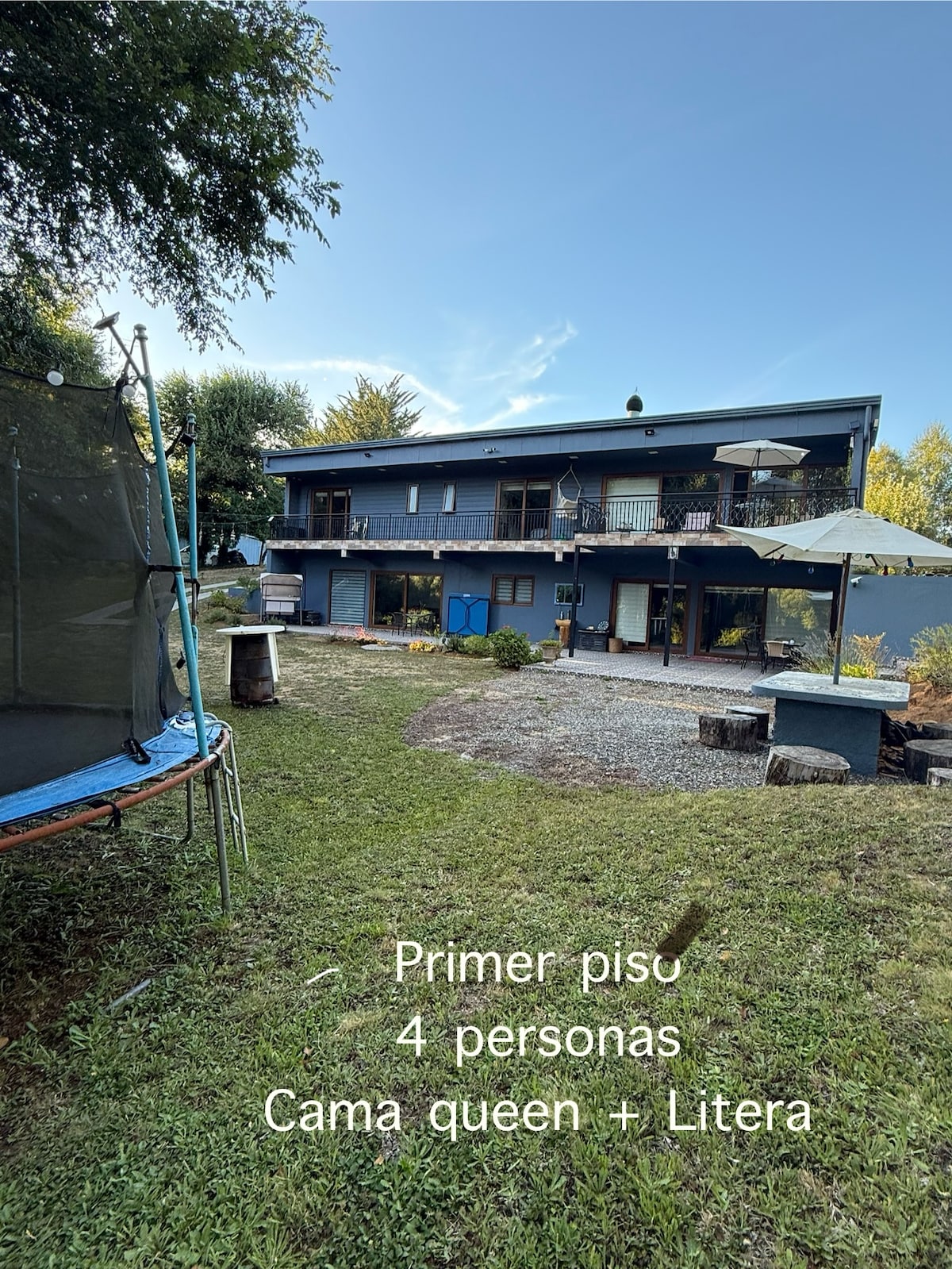 The exterior of the property features a spacious lawn with a trampoline. The two-story building showcases multiple balconies and outdoor seating areas under shaded umbrellas. Clear pathways lead through the garden, enhancing the sense of privacy and tranquility.