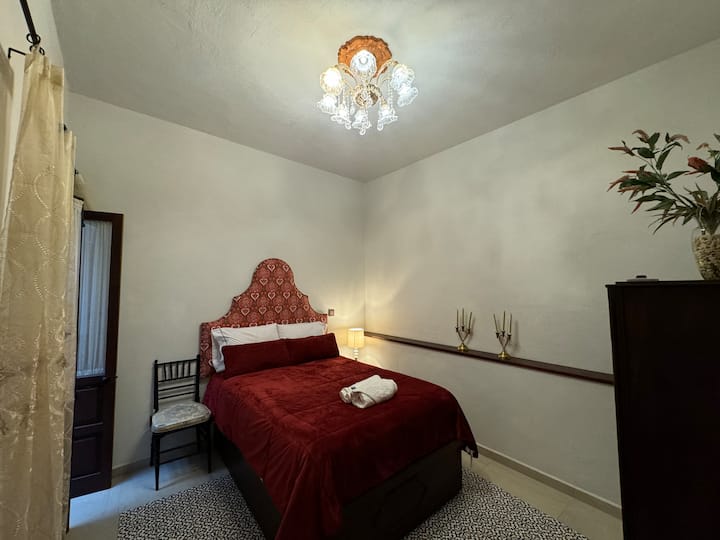 Encantadora recámara con cama matrimonial, lámpara de cristal y detalles clásicos que resaltan el carácter colonial de la casa.