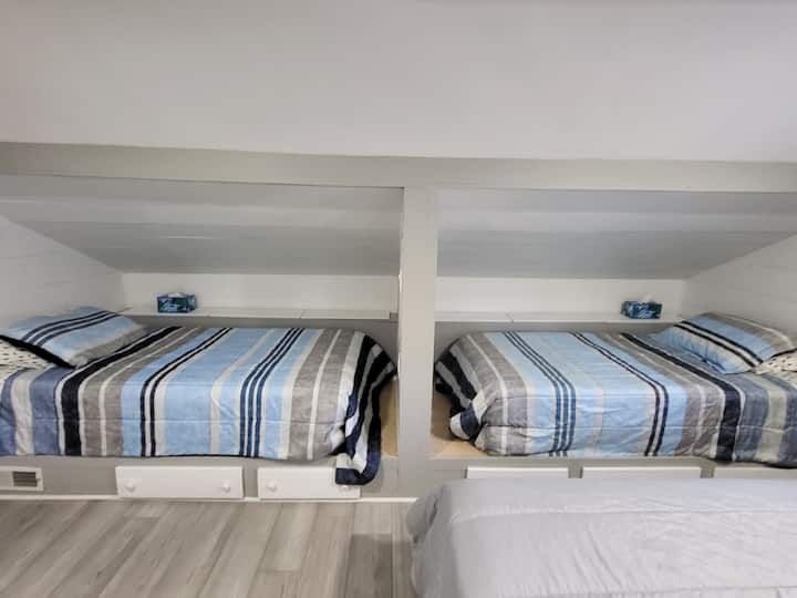 Camas individuales en alcobas privadas.  Cama tamaño queen visible a la derecha