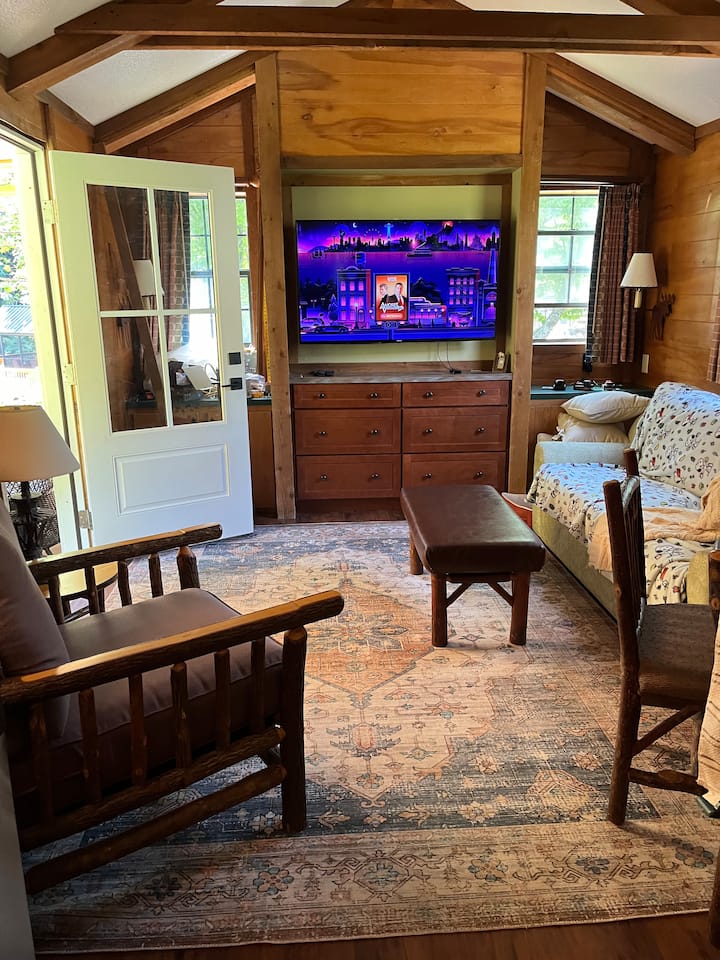 Уживајте во седењето во дневна соба со задна врата отворена за звуците на потокот и распеаните птици.