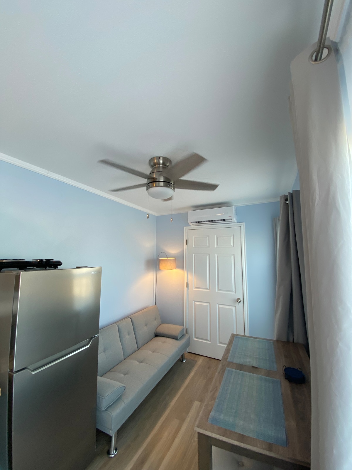 تم تأثيث منطقة المعيشة بمروحة سقف وفوتون صغير ومصباح وطاولة/مقاعد لشخصين.