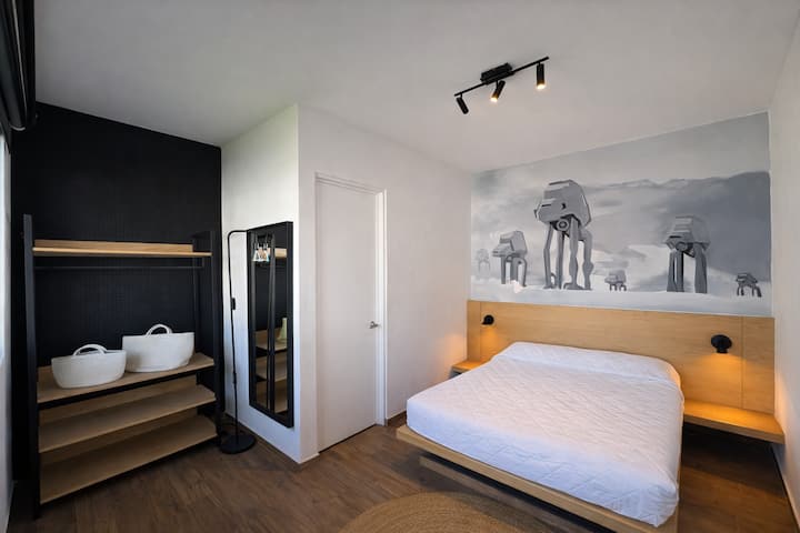 غرفة واسعة بسرير مزدوج وحمام خاص. إذا كنت من محبي حرب النجوم، فستحب هذه اللوحة الجدارية لمشاية AT - AT!