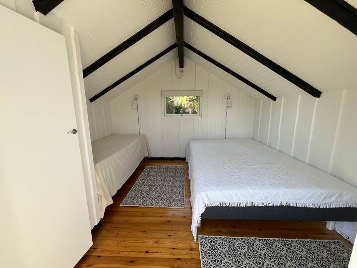 צריף עם מיטת 140 ס"מ ומיטת יחיד אחת, כמו גם 2 מזרנים יחיד נוספים.