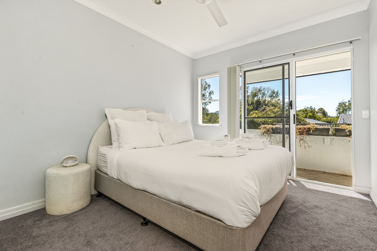 Dormitorio luminoso y acogedor con una cama tamaño queen y sábanas suaves. Esta habitación no tiene su propio aire acondicionado, pero 3 unidades de aire acondicionado en la casa mantienen baja la temperatura de los dormitorios y el ventilador de techo proporciona un flujo de aire adicional.