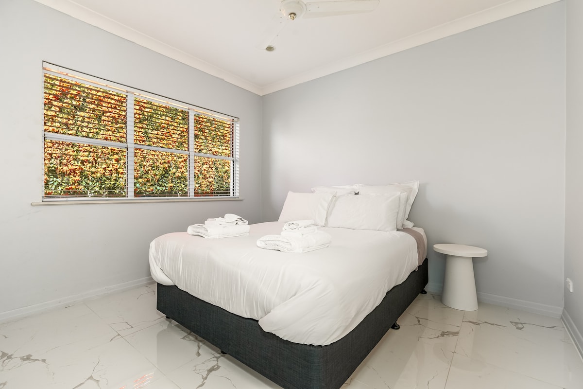 Dormitorio luminoso y acogedor con una cama tamaño queen y sábanas suaves. Esta habitación no tiene su propio aire acondicionado, pero 3 unidades de aire acondicionado en la casa mantienen baja la temperatura de los dormitorios y el ventilador de techo proporciona un flujo de aire adicional.