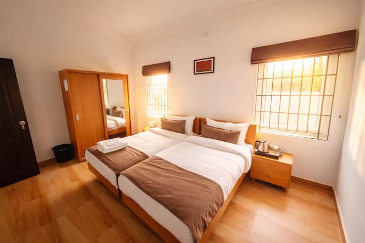 Acogedora habitación doble con dos cómodas camas de una plaza, armario de madera, hervidor de agua junto a la cama y calefacción por suelo radiante. Luz natural gracias a las ventanas orientadas a Nilgiri. Perfecto para 2 amigos, hermanos o padres e hijos.