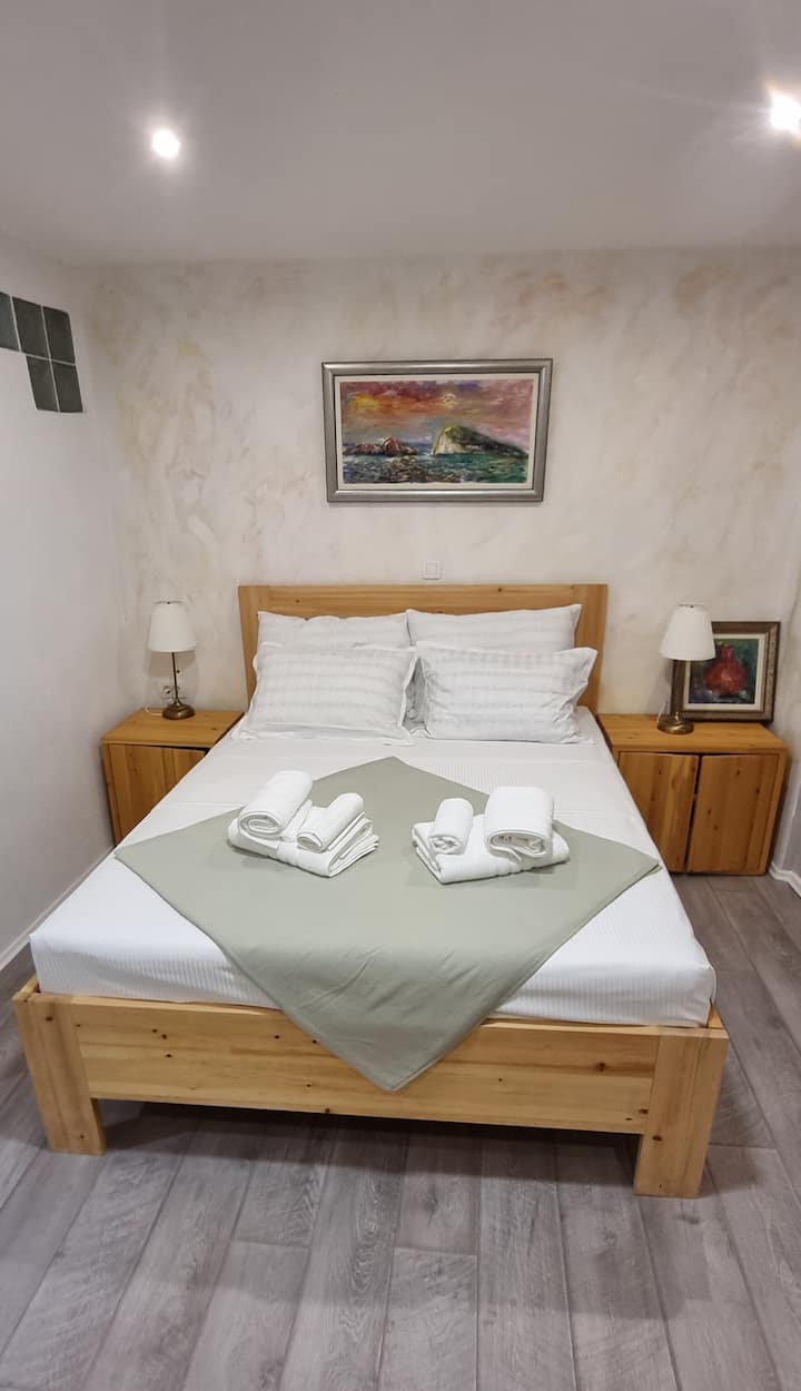 Dvostruki krevet s noćnim svjetiljkama i malim ladicama.