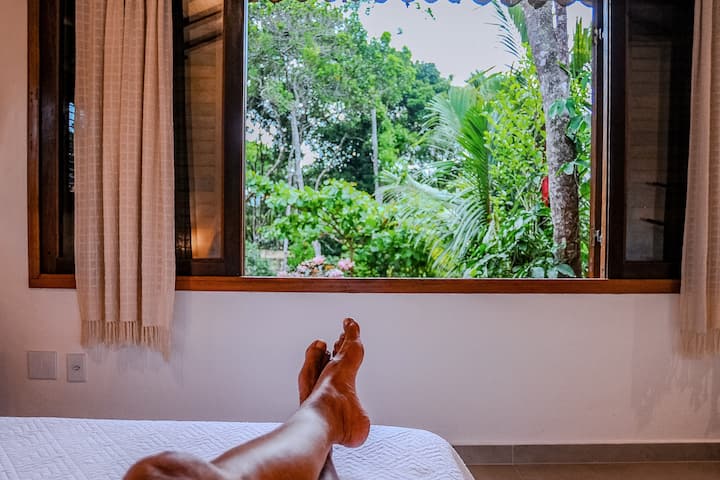 tumbado en la cama se puede ver el jardín con mucho verde