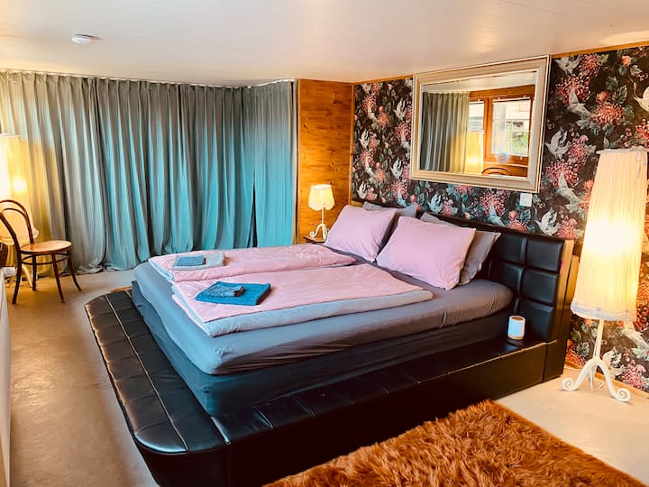 Prvá spálňa s manželskou posteľou a rohovou vaňou sa nachádza na prízemí a susedí so vstupným priestorom. 
Vstupným priestorom vstúpite priamo do 1. kúpeľne.