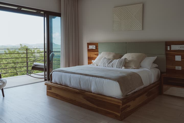 Elegantná suita na druhom poschodí s manželskou posteľou, televízorom Smart TV, klimatizáciou a vlastnou terasou s výhľadom na hory – pokojné prostredie pre rannú kávu alebo sledovanie západu slnka. Vlastná kúpeľňa obsahuje čisté uteráky a prvotriedne vybavenie.