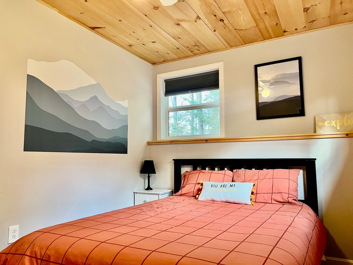 Ova spavaća soba na nižoj razini ima bračni krevet s komodom i ormarom. 