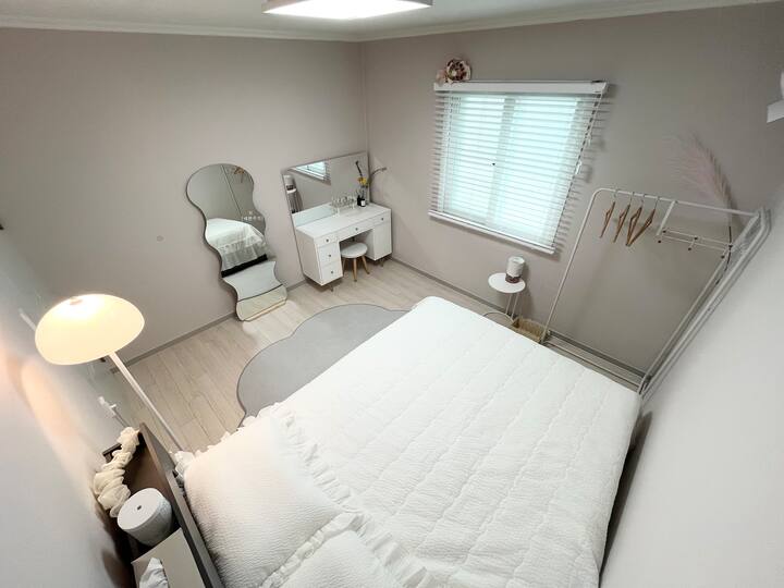 Segundo quarto aconchegante com uma cama queen-size, penteadeira e espelho de corpo inteiro elegante.