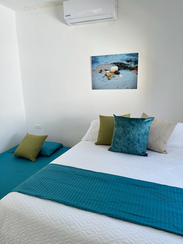 Cuenta con una cama doble y una individual, ambas con almohadas suaves para un buen descanso. Tiene aire acondicionado para mayor confort. La ventana grande aporta luz natural, y las persianas te permiten ajustar la claridad y privacidad.