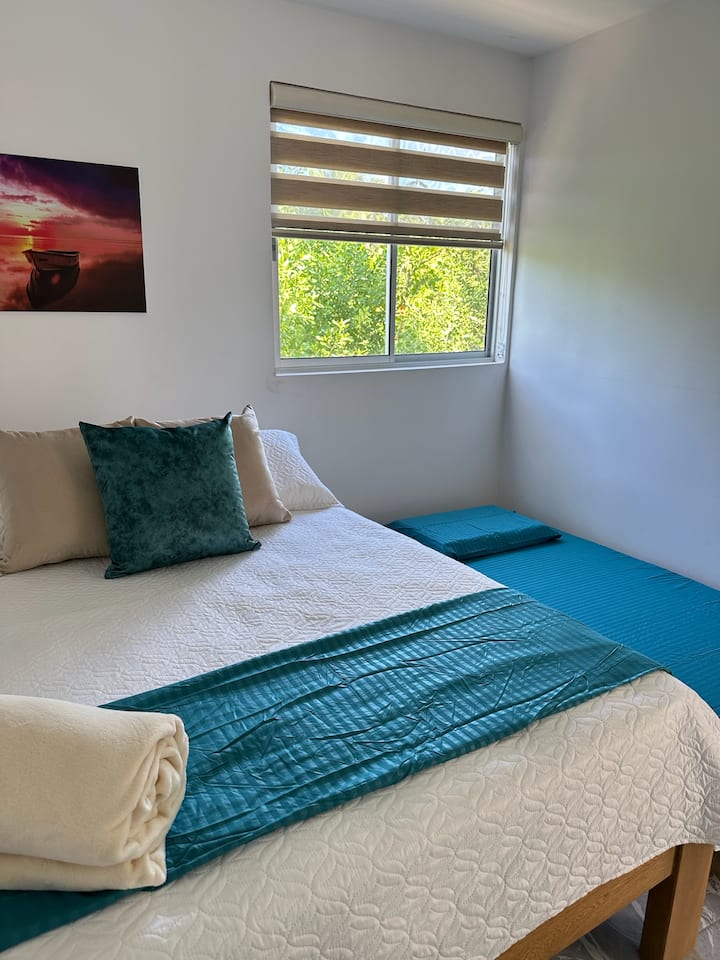 Cuenta con una cama doble y una individual, ambas con almohadas suaves para un buen descanso. Tiene aire acondicionado para mayor confort. La ventana grande aporta luz natural, y las persianas te permiten ajustar la claridad y privacidad.