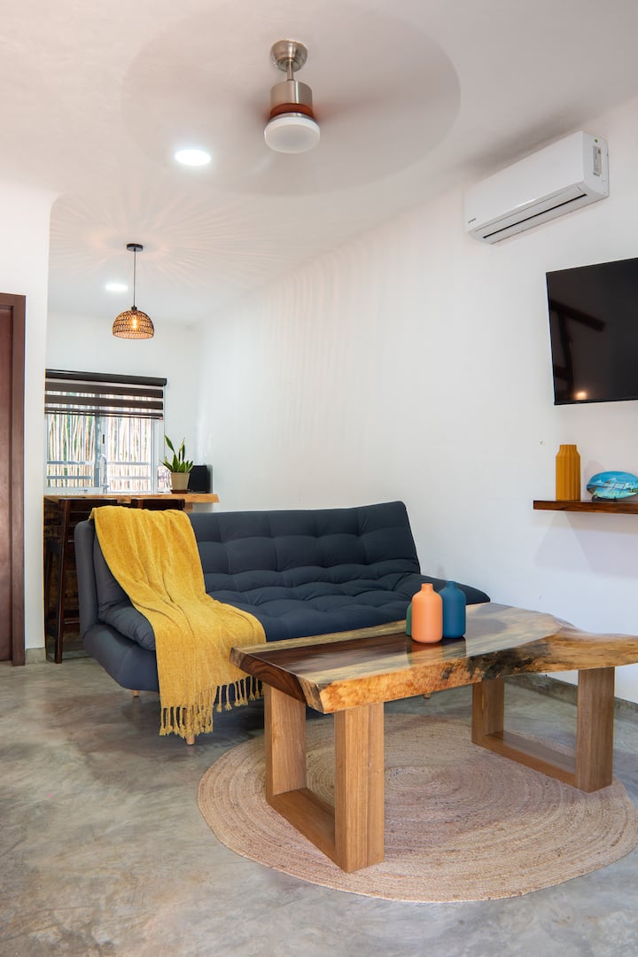 Приземен етаж с малка стая, кухня. Къщата има дървен декор, вази и ръчно изработена постелка.