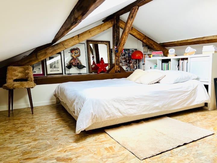 La cama doble en la gran habitación en el entresuelo que se abre al cielo