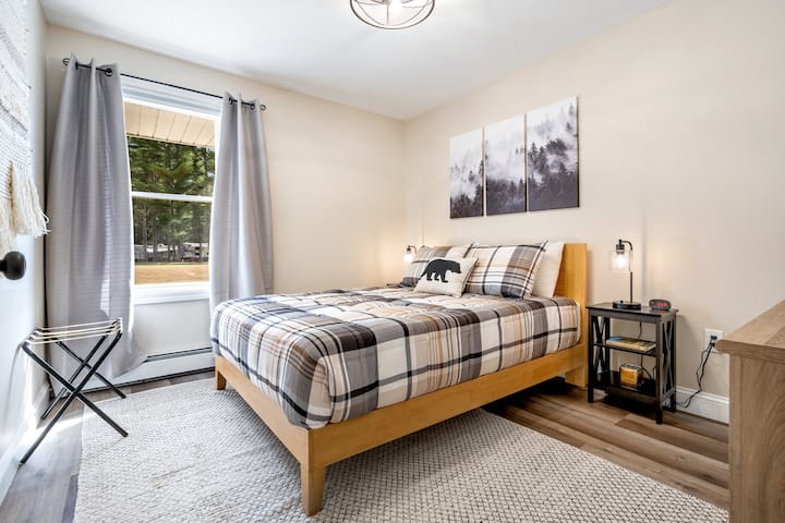 Serene Bedroom: Bright light pours in, highlighting a stylish queen bed and rustic-chic decor.