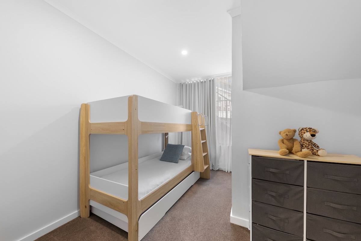 غرفة النوم الثالثة: سرير بطابقين ومرتبة مفردة على سرير قابل للسحب.  ستائر تعتيم ومكيف هواء سبليت لراحتك.  يرجى الملاحظة: السرير العلوي والسرير القابل للسحب هما مرتبة رغوية - قد يرغب البالغون في استخدام كليهما للحصول على راحة إضافية اعتمادًا على حجم مجموعتك.