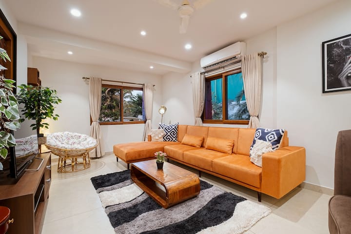 Living room a Large Sofa with a Lounger with 43”inch smart TV and AC with high speed Wi-Fi also with cozy, warm lighting with Large coffee tables with some planters.