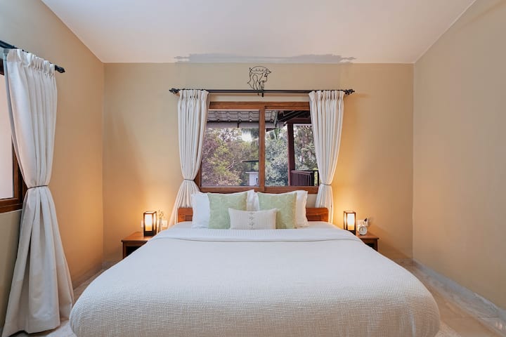 Ensuite Bedroom Located in the first Floor with a King Size Mattress , a cozy space with an attached Bathroom overlooking the Pool and the entrance area of your home away from home.