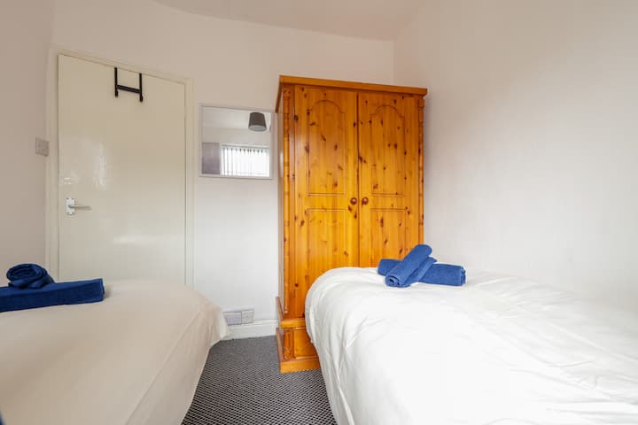 Un cómodo dormitorio con dos camas individuales, todo con ropa de cama y toallas limpias para una experiencia tranquila.