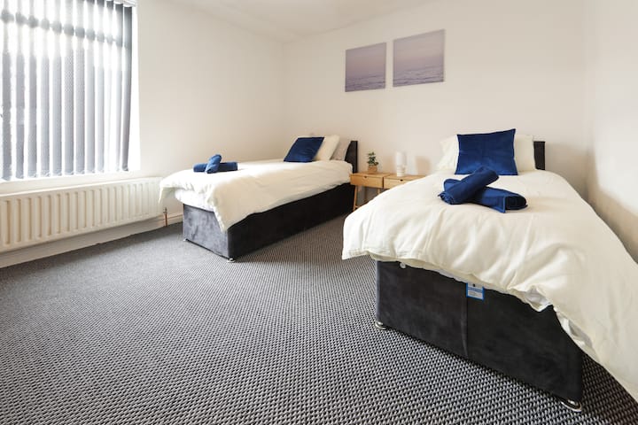 Un dormitorio espacioso con 2 camas individuales, cada una vestida con sábanas y toallas limpias.
