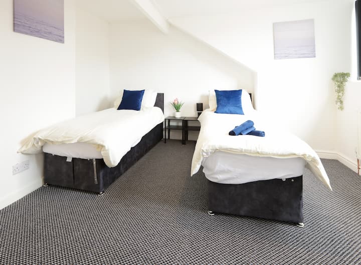 Un acogedor dormitorio con dos camas individuales, cada una preparada con ropa de cama y toallas limpias para una estancia agradable.


