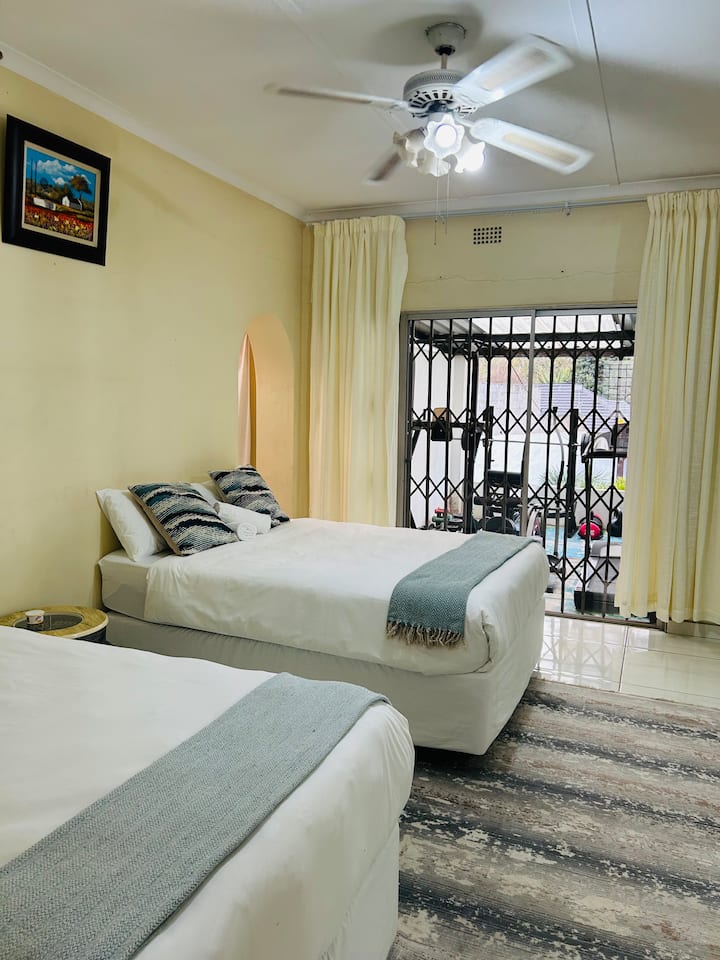 غرفة نوم داخلية (مرحاض مع دش) سرير ربعي وسرير كوين وخزانة مرآة وباب منزلق يؤدي إلى منطقة الصالة الرياضية