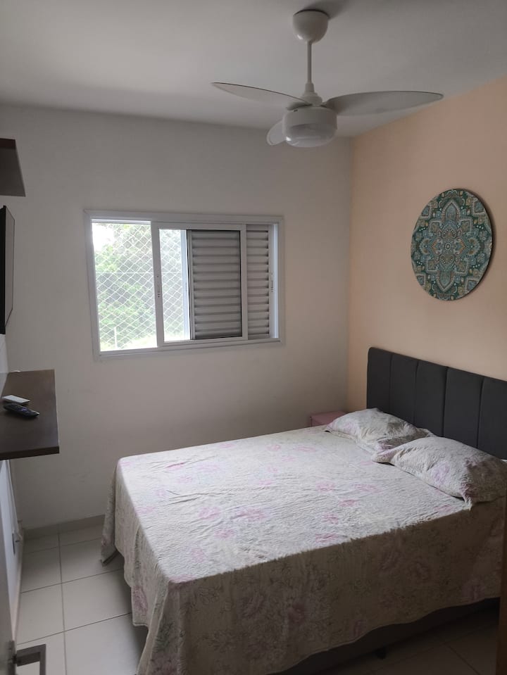 Cama de casal, roupas de cama, travesseiros, televisão 32" smart, ventilador de teto, ventilador portátil e guarda roupas.