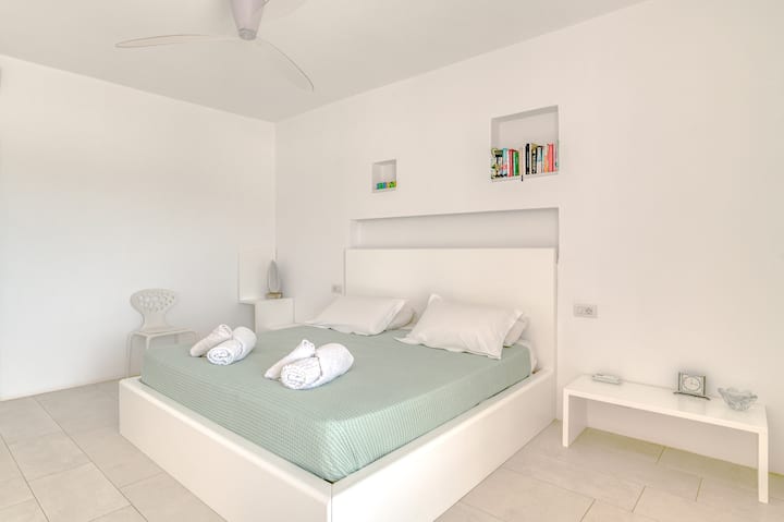 Chumba kikubwa cha kulala chenye baraza la kujitegemea, kabati la kuingia na bafu la chumbani lenye sinki mbili.