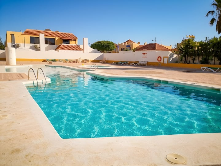 Piscina comunitaria de agua cristalina entre palmeras: el mejor plan para los días de calor.