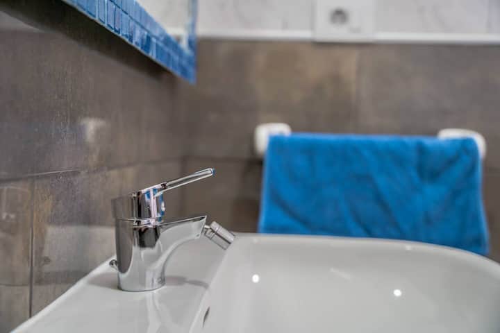 Detalle del baño con bañera, grifería moderna y toalla azul: cómodo para darse un buen baño.