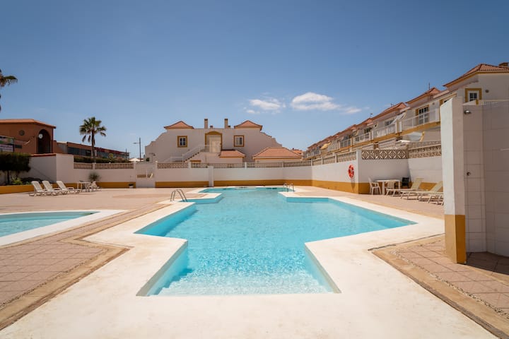 Gran piscina comunitaria rodeada de solárium: un chapuzón a pocos pasos del apartamento.