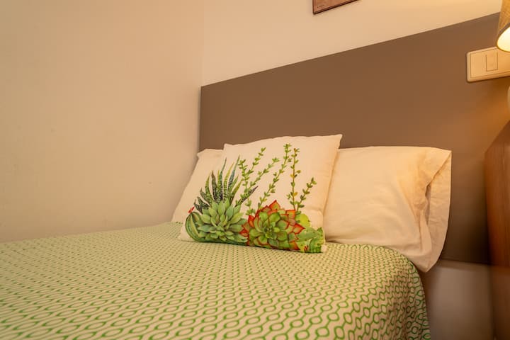 Cama de matrimonio del dormitorio 2 con detalles en verde: descanso agradable tras la playa.