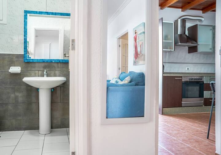 Baño con lavabo de pie y espejo, abierto al resto del apartamento: limpio y luminoso.