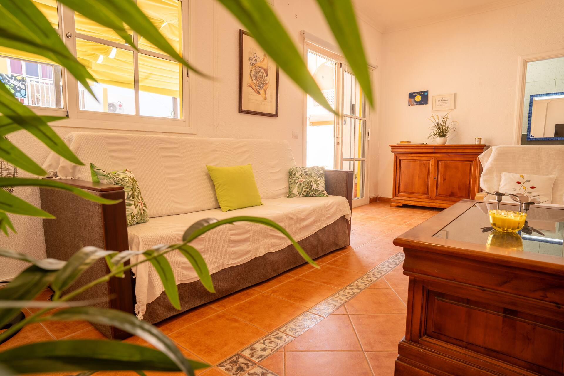 Salón luminoso con sofá, cómoda de madera y suelo de barro: ambiente cálido y acogedor.