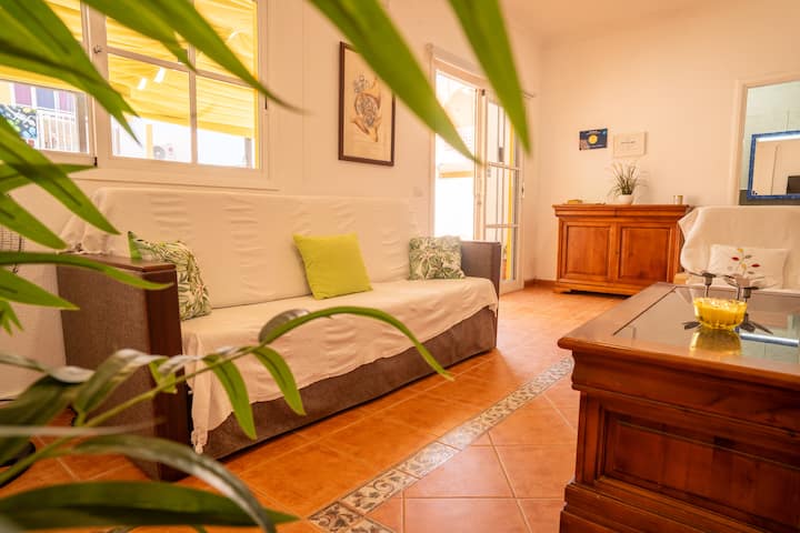 Salón luminoso con sofá, cómoda de madera y suelo de barro: ambiente cálido y acogedor.