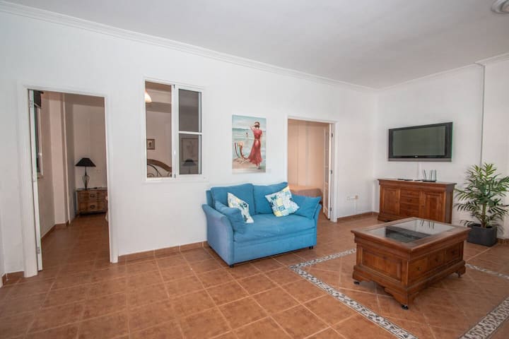 Salón con sofá azul, mesa de centro y TV, con acceso al resto del apartamento: espacio confortable.