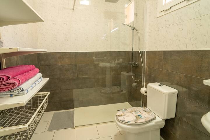 Baño completo con ducha, inodoro y toallas preparadas: impecable y listo para tu llegada.
