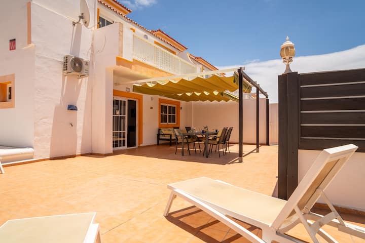 Patio exterior con zona de comedor bajo el toldo y tumbonas: el exterior perfecto para el buen tiempo.